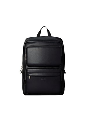 Sort læderrygsæk med to forlommer med lynlås og et håndtag øverst, Calvin Klein-logo på den nederste lomme.