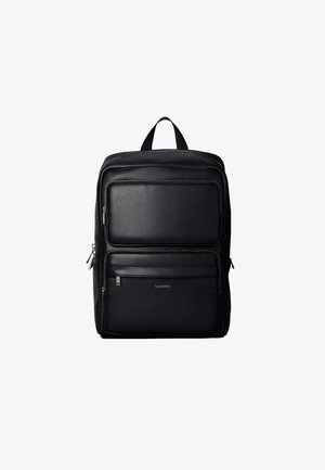 Sort læderrygsæk med to forlommer med lynlås og et håndtag øverst, Calvin Klein-logo på den nederste lomme.