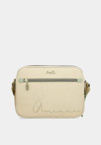 Bolso bandolera sintético beige con un bolsillo frontal con cremallera, logo en relieve y detalles en color verde. Presenta una textura suave y forma rectangular.