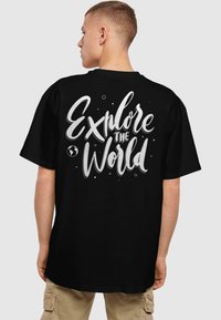 Sortærmet sort T-shirt med hvid tekst "Udforsk Verden" samt et globe grafisk motiv, lavet af glat bomuldsstof.