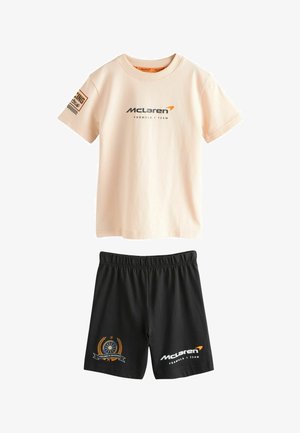 T-shirt beige à manches courtes de l'équipe McLaren de Formule 1 et short noir avec logos et écussons à thème de course.