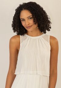 Witte geplooide mouwloze blouse met een gelaagd ontwerp, met een gladde halslijn en doorschijnende details op de schouders.