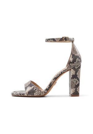Sandale à talon haut avec talon bloc, bride à la cheville et bout ouvert en motif peau de serpent gris et beige, vue de côté sur fond blanc.