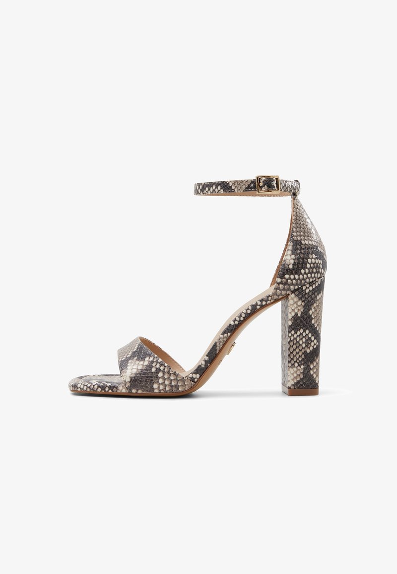 Sandale à talon haut avec talon bloc, bride à la cheville et bout ouvert en motif peau de serpent gris et beige, vue de côté sur fond blanc.