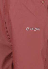 Rode waterdichte jas met een gladde textuur, voorzien van een logo in het wit. Inclusief drukknopdetail en contrasterende zwarte stiksels.
