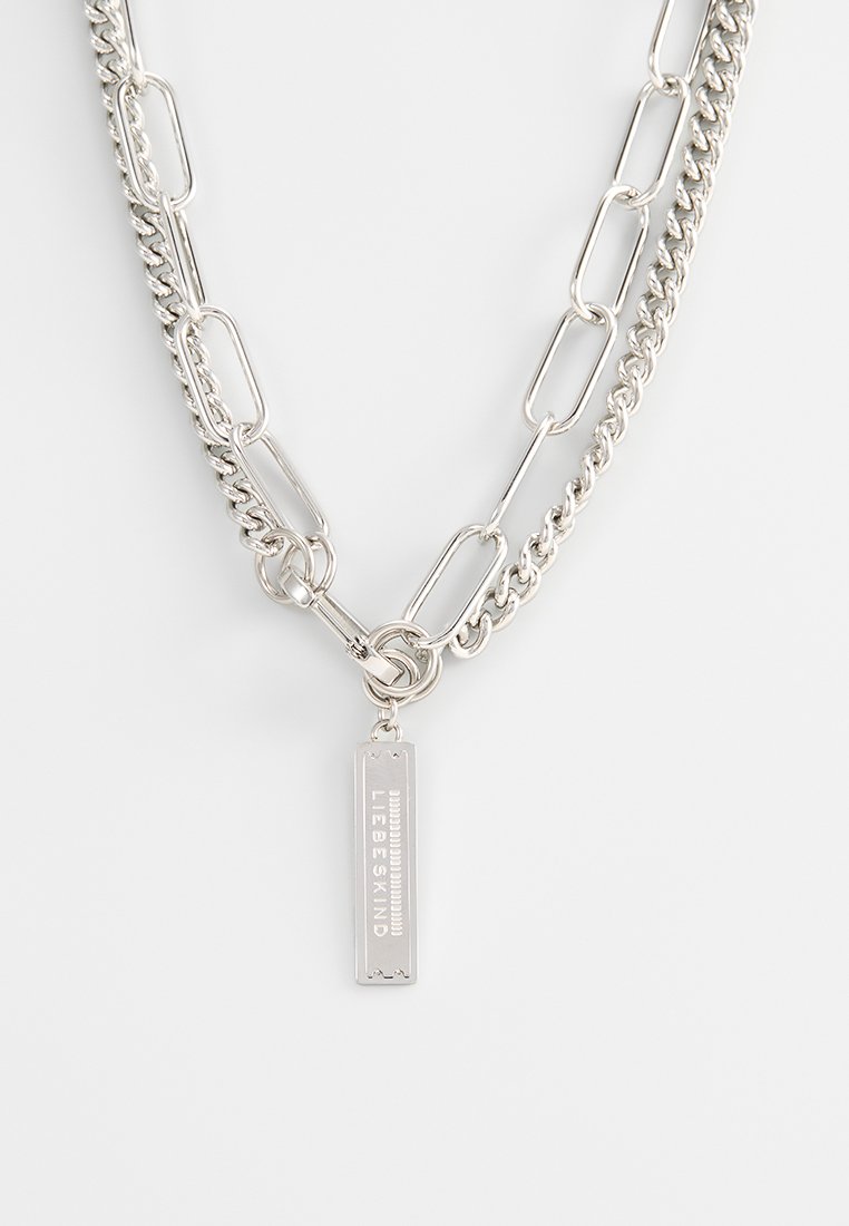 Silberne Kettenhalskette mit gemischten Gliedern, darunter ovale und runde Formen. Auffälliger Anhänger mit graviertem Text.