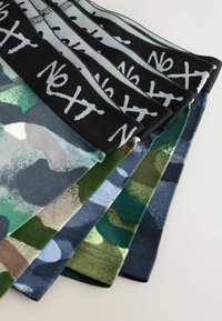 Fem par boxer briefs til mænd i forskellige camouflage mønstre, med sorte elastiske taljebånd med hvid tekst "NEXT".