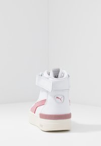 High-top sneakers in white leather with pink accents, featuring a velcro strap and textured rubber sole. PUMA logo on the side.