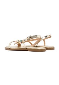 Gouden metallic sandalen met een platte zool, voorzien van een decoratieve accent van meerkleurige edelstenen en een verstelbare enkelband. Gladde textuur.