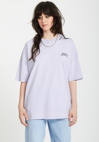 Lichtpaarse oversized T-shirt gemaakt van katoen, met een grafische print op de linkerkant van de borst. De mouwen zijn wijd, wat zorgt voor een ontspannen pasvorm.