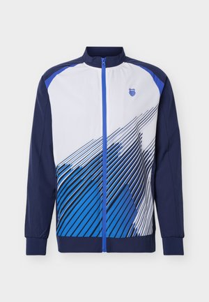 Chaqueta deportiva para hombre con cremallera, mangas azul marino, parte delantera blanca y patrón de rayas diagonales azules, con un pequeño logo de escudo en el pecho.