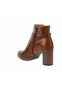 Bottine en cuir marron avec un bout arrondi, fermeture éclair sur le côté et un talon en bois empilé. Présente une couture minimaliste et un design épuré.