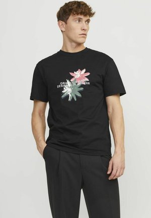 Camiseta de algodón negra con un diseño gráfico de flores en tonos rosa y verde, con un texto en blanco que dice "Originals 1990 Diseñado en Copenhague."