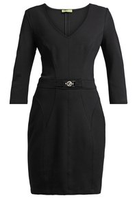 Robe noire longueur genou avec manches trois-quarts, encolure en V, détails de couture et ceinture avec boucle métallique ronde à la taille.