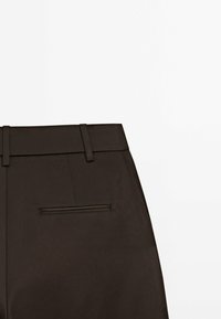 Brown trousers featuring a smooth texture, slim design, and a back pocket with a subtle seam detail. Fabric appears lightweight.