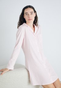 Chemise de nuit en vichy rose avec manches longues, devant à boutons et poche sur la poitrine. Tissu doux avec une coupe décontractée, design jusqu'aux genoux.