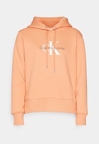 Orange hooded sweatshirt with a drawstring. Front features a white "CK" logo and "Calvin Klein Jeans" text. Soft fabric with ribbed cuffs.