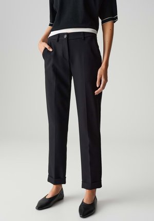 Schwarze maßgeschneiderte Hose mit geradem Sitz, mit einem Frontknopfverschluss, umgeschlagenem Saum und Seitentaschen. Glatte Stofftextur.