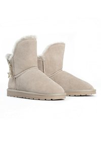 Stivali alla caviglia in suede beige con una morbida fodera in pelliccia bianca e un charm a stella decorativo sulla parte laterale, dotati di suola in gomma con grip.