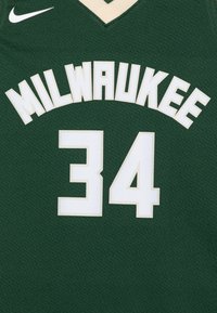 Žalias krepšinio marškinėliai su baltais užrašais. "MILWAUKEE" išlenktas virš skaičiaus "34", abu apvesti kreminės spalvos kontūru. Nike logotipas viršutiniame kairiajame kampe.