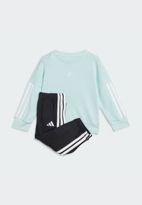 Light blue sweatshirt with white stripes on sleeves, paired with black pants featuring white stripes along the sides. Both with logo accents.