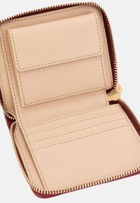 Beige leren portemonnee met meerdere kaartsleuven, een klepzak en een gouden rits langs de rand, geopend tegen een witte achtergrond.