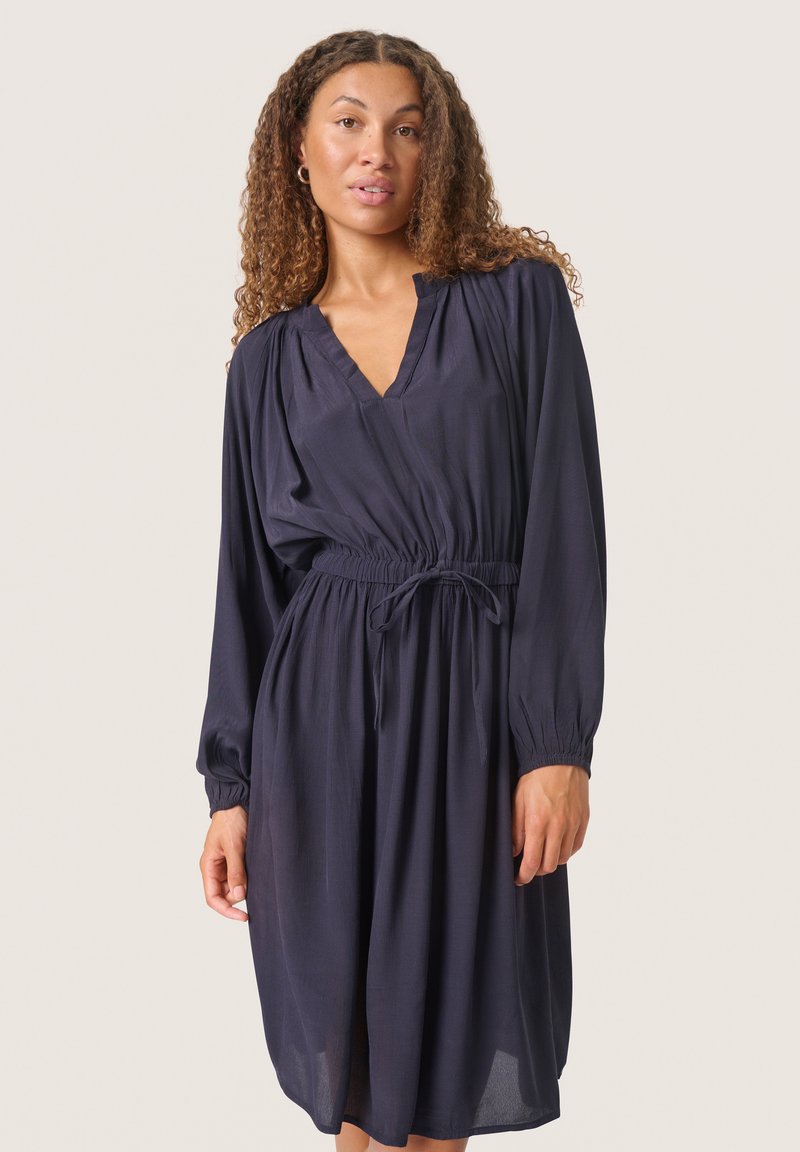 Navyblaues langärmliges Kleid mit V-Ausschnitt, elastischem Bund und Bindedetail, aus leichtem Stoff für eine fließende Silhouette.