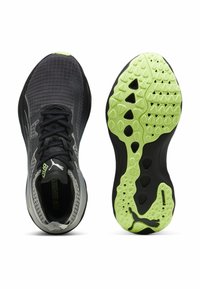 Scarpe da corsa nere con una parte superiore testurizzata, dettagli in verde lime sulla suola e una suola con un motivo che presenta elementi di grip variabili.