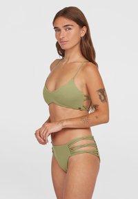 Olivgrönt bikini-set med en triangulär bh och bikinitrosor med sidostöd. Mjuk textur och minimalistisk design med justerbara remmar.