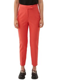 Op maat gemaakte koraalkleurige broek met een cropped ontwerp, een platte voorkant en zijzakken, gemaakt van een gladde stof. Gepaard met zwarte platform schoenen.