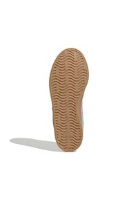 Rubberen buitenzool van een sneaker met een golvend profiel, lichtbruine kleur en geperst merkembleem, toont textuur en gripontwerp.