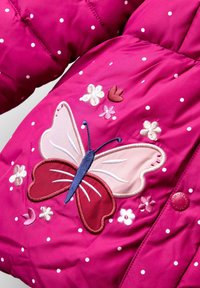 Rosa Pufferjacke mit weißen Punkten, besticktem Schmetterling und Blumen in verschiedenen Rosatönen, Lila und Rot, mit einem runden Druckknopf.