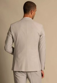 Lichtgrijze blazer, slim fit ontwerp, gladde textuur, enkele split achteraan, met bijpassende broek, minimalistische afwerking op de mouwen.