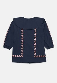Blusa a maniche lunghe blu navy con ampio colletto e ricami di ciliegie rosa lungo le maniche e i lati posteriori.