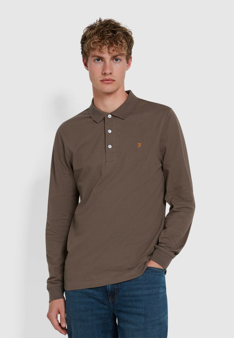 Polo a maniche lunghe marrone con colletto, tre bottoni bianchi e un piccolo logo giallo sul lato sinistro del petto. Texture semplice.