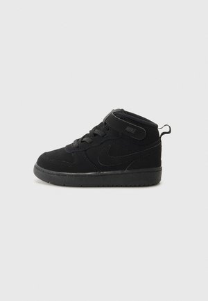 Baskets montantes Nike noires pour tout-petit avec lacets, une sangle Velcro et une languette sur un fond gris clair uni.