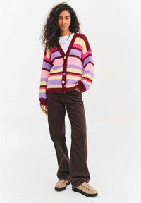 Wielokolorowy dziergany kardigan z pionowymi paskami w kolorach różowym, fioletowym, żółtym i bordowym, z dekoltem w serek i czterema guzikami.