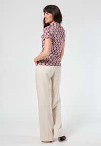 Blusa a maniche corte in tessuto pois bordeaux e bianco, abbinata a pantaloni color crema, caratterizzata da un fit rilassato e una sottile trama.