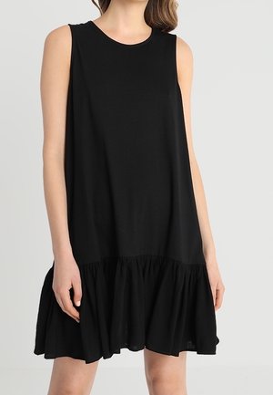 Zwarte mouwloze jurk gemaakt van zachte stof, met een losse pasvorm en een gerafelde zoom. Soepele textuur met een knielengte ontwerp.