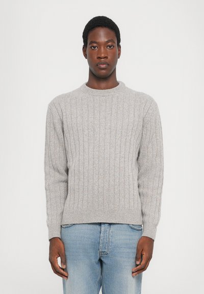 Grau gerippter Strickpullover mit Rundhalsausschnitt, strukturiertem Material und langen Ärmeln, kombiniert mit hellblauen Jeans.