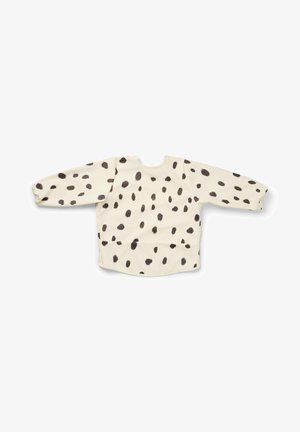 Langærmet beige småbørnsforklæde med sorte uregelmæssige pletter, elastiske manchetter og en afrundet halsudskæring, lagt fladt mod en hvid baggrund.