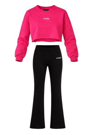 Felpa corta rosa con scritta "PYREX" abbinata a pantaloni neri a zampa con scritta "PYREX" sull'anca sinistra.