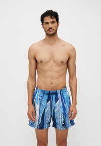Blue patterned swim shorts featuring a drawstring waistband, an abstract design with varying shades of blue, and a lightweight fabric.