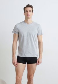 T-shirt gris à manches courtes en mélange de coton, associé à un slip noir. Le t-shirt a un col rond et est ajusté.
