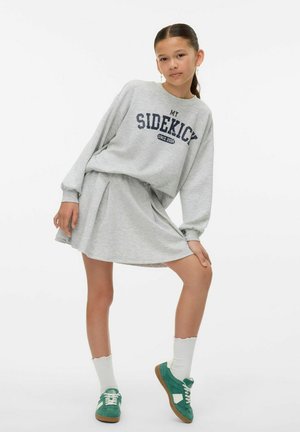 Abito felpa grigio con la scritta "MY SIDEKICK" stampata in blu navy, vestibilità rilassata, gonna plissettata, abbinato a scarpe da ginnastica verdi e calzini bianchi.
