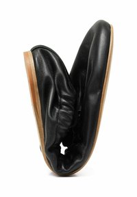 Zapato de cuero negro con una textura suave y arrugada y un diseño flexible. Suela de goma natural para agarre y durabilidad.