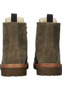 Gröna mockaboots till ankeln med en mjuk foder, gummisula och en träklack. Har en ögla för lätt påtagning och subtila sömnadsdetaljer.