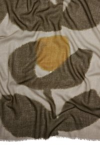 Chusta w lekkim materiale w wzory, z dużymi brązowymi i żółtymi abstrakcyjnymi kształtami na kremowym tle, z postrzępionymi brzegami.