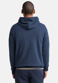 Marineblauwe hoodie met een trekkoordkap, raglanmouwen en geribbelde boorden. Zachte textuur met een eenvoudig, schoon achterontwerp.