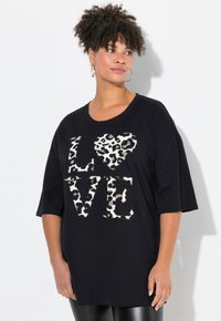 T-shirt noir surdimensionné arborant "LOVE" en lettres gras, avec un cœur et des accents de lettres en imprimé léopard. Manches courtes, coupe décontractée.